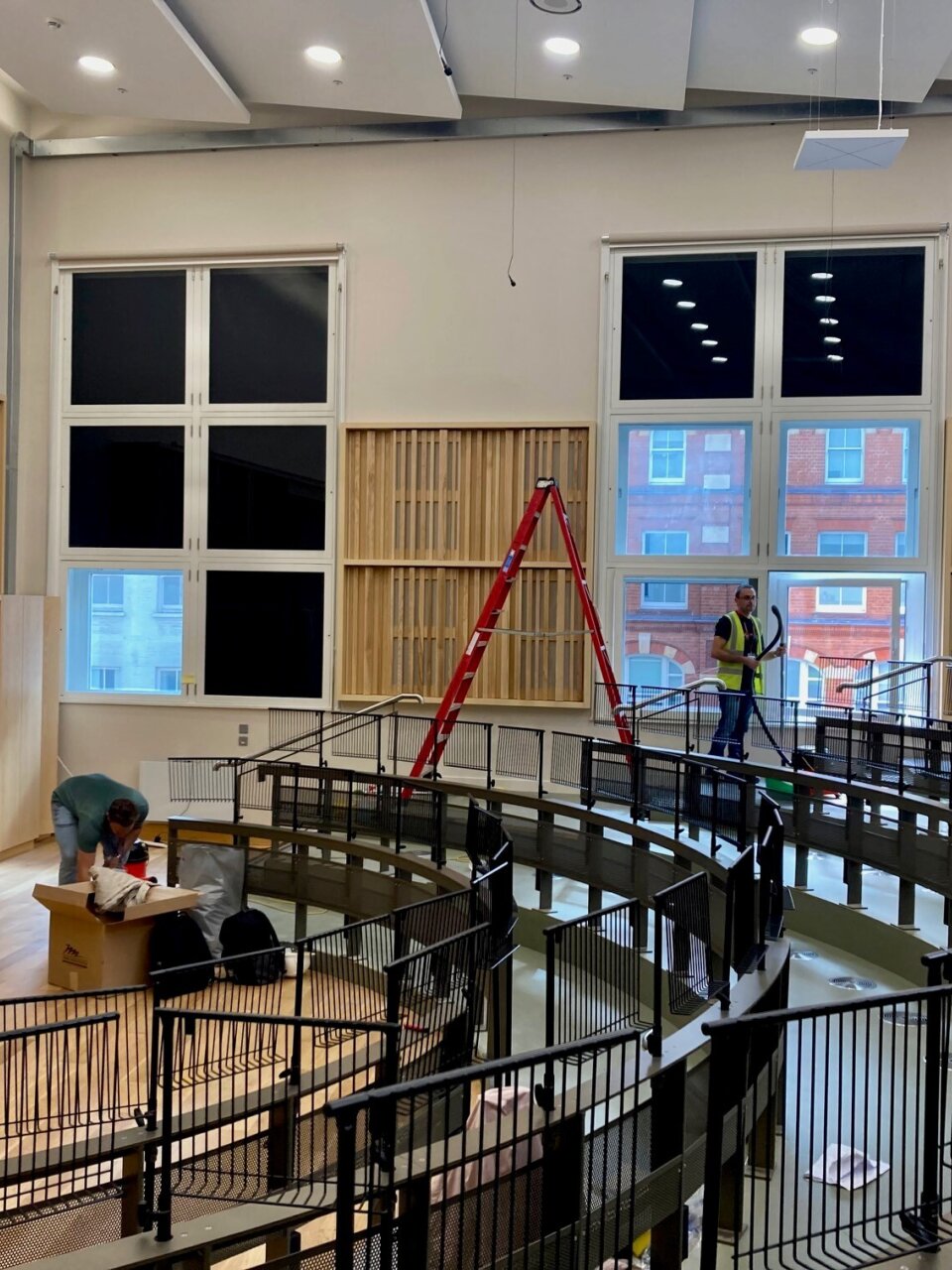 Workers install music stands and seating in a theatre.