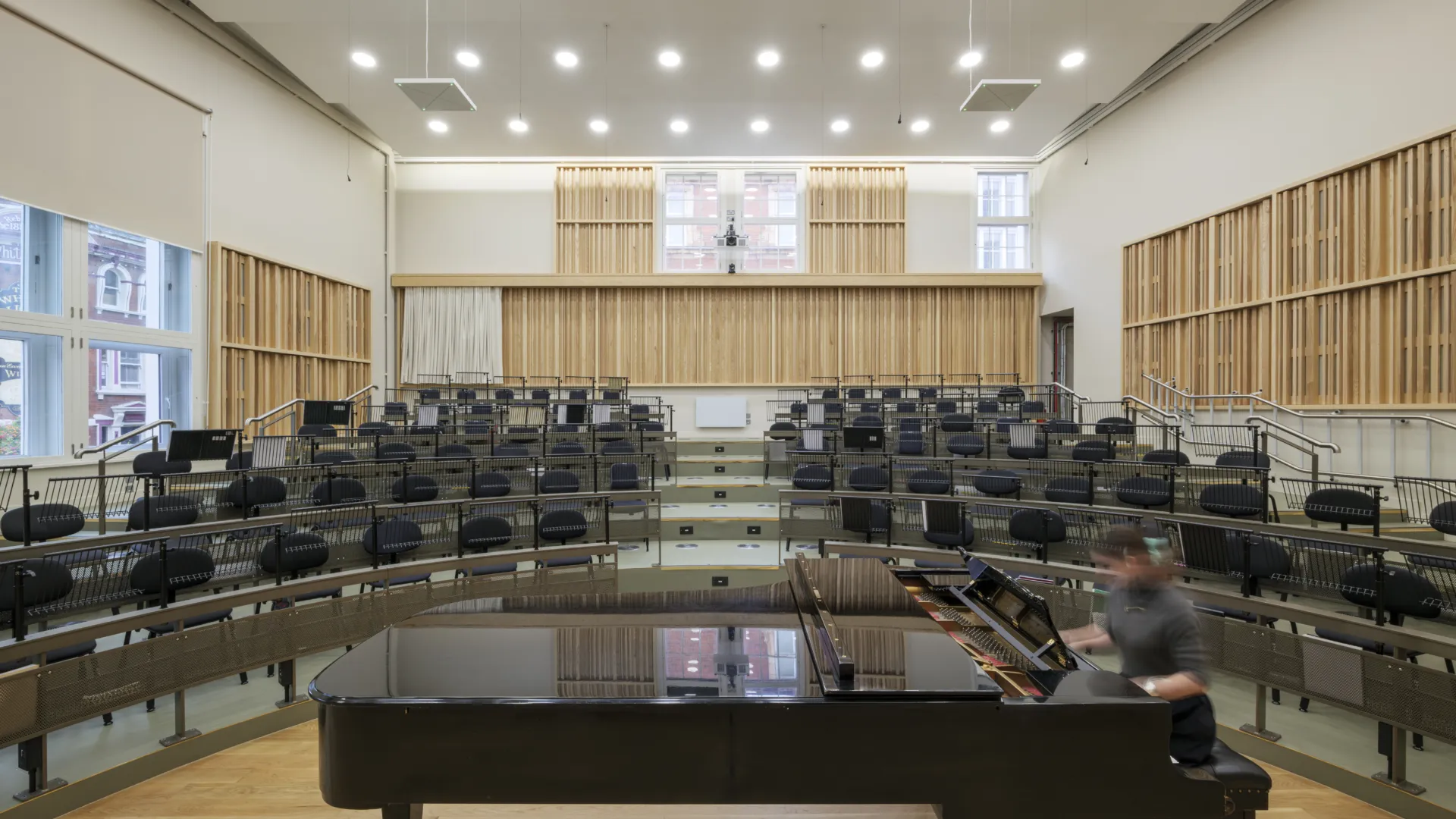 Grand piano inside a music rehearsal room with many rows of seats