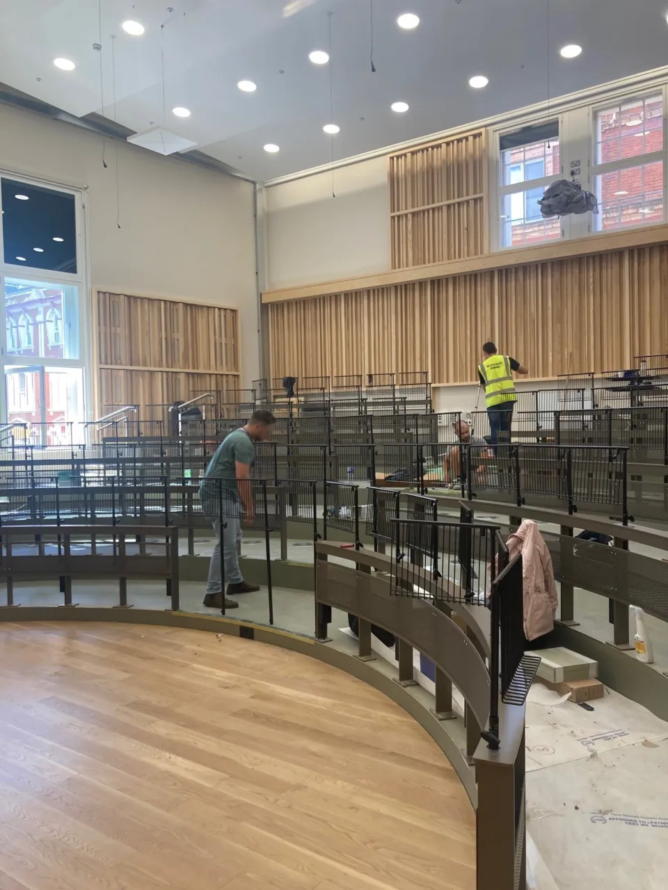 Workers install music stands and timber panelling inside a theatre.
